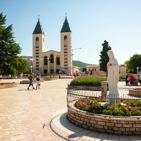 Medjugorje Sanctuary in Bosnia and Herzegovina. In the foreground is the vigin Mary statue and in the background is the parish church.