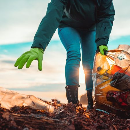 A,Volunteer,Collects,Garbage,On,A,Muddy,Beach.,Close-up.,The